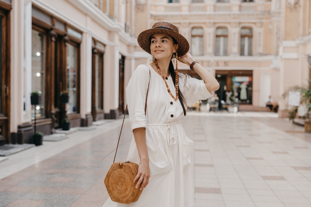 devojka u boho stil, bela haljina, šešir i torbica na njoj